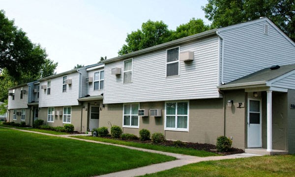 a row of houses with a sidewalk and green grass