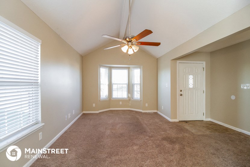 an empty living room with a ceiling fan and a window