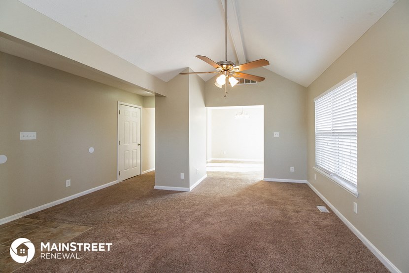 an empty living room with a ceiling fan and a large window