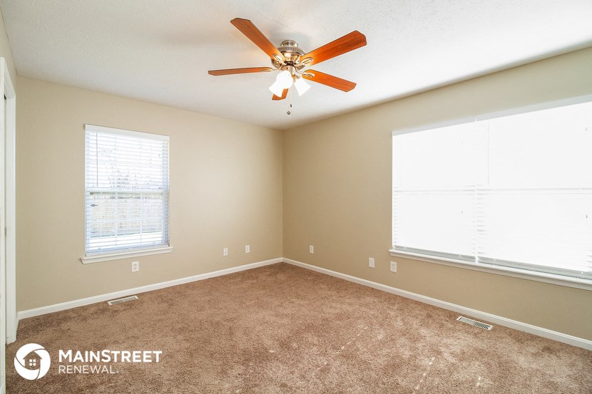 the master bedroom has a carpeted floor and a ceiling fan