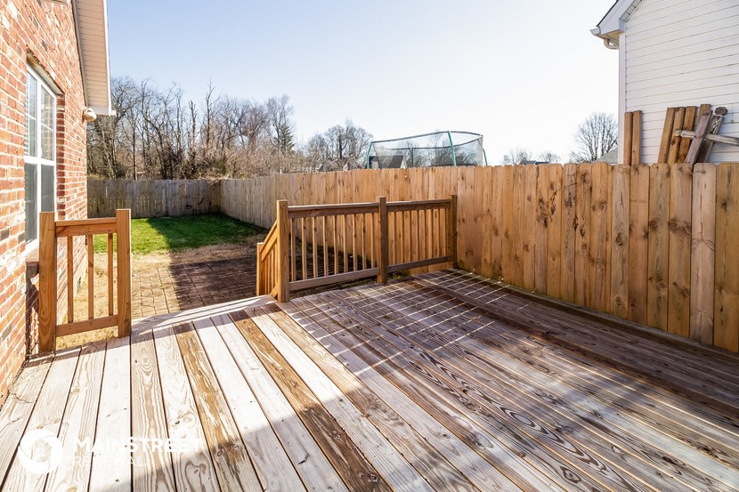 a backyard deck with a privacy fence and a swing