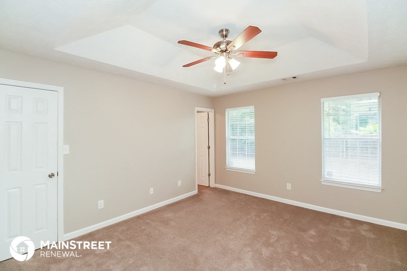 the master bedroom has a carpeted floor and a ceiling fan