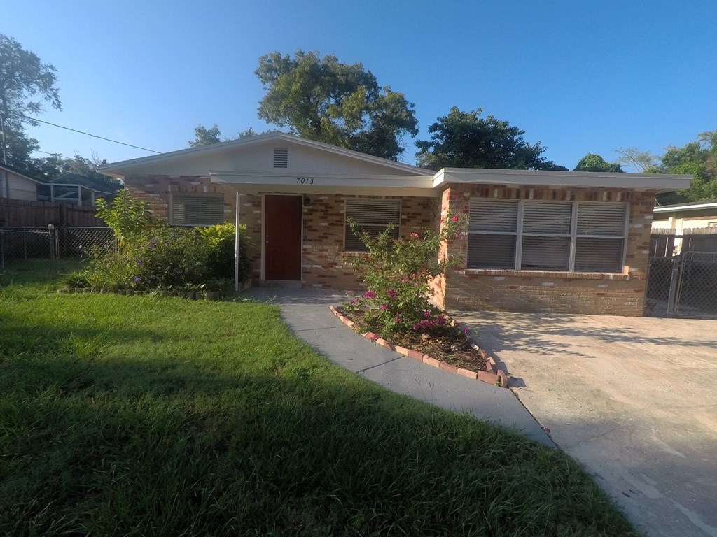 a small brick house with a porch and a driveway