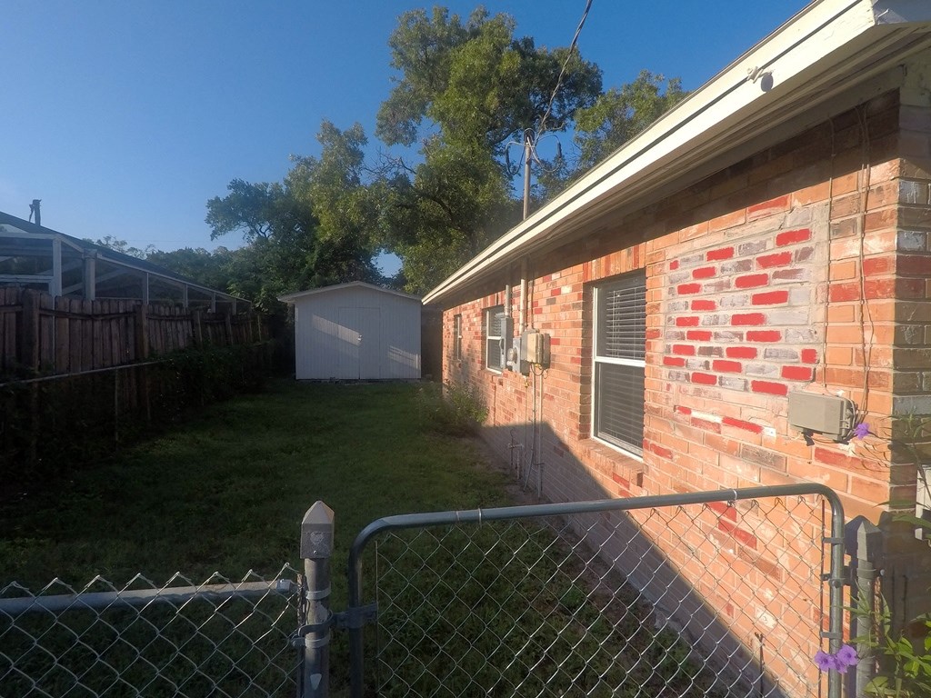 the side of a brick house with a fence and a yard