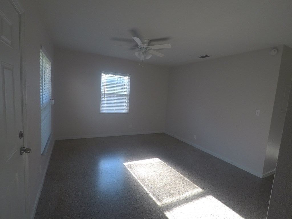 an empty room with a ceiling fan and a window