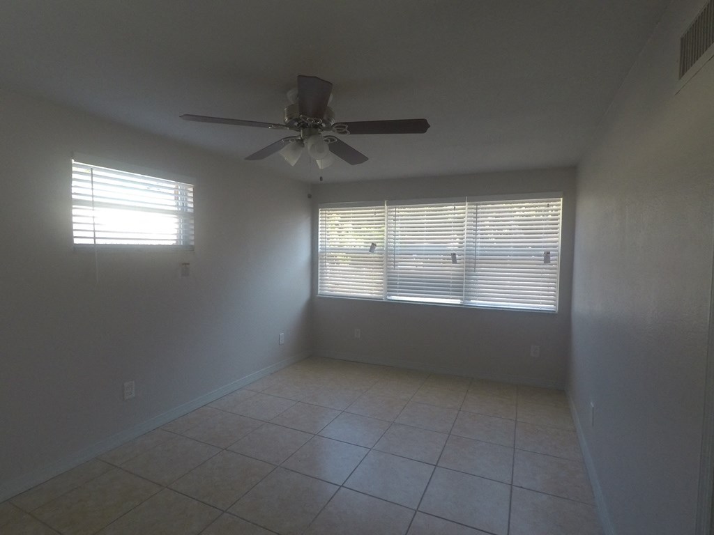 an empty living room with a ceiling fan and a window