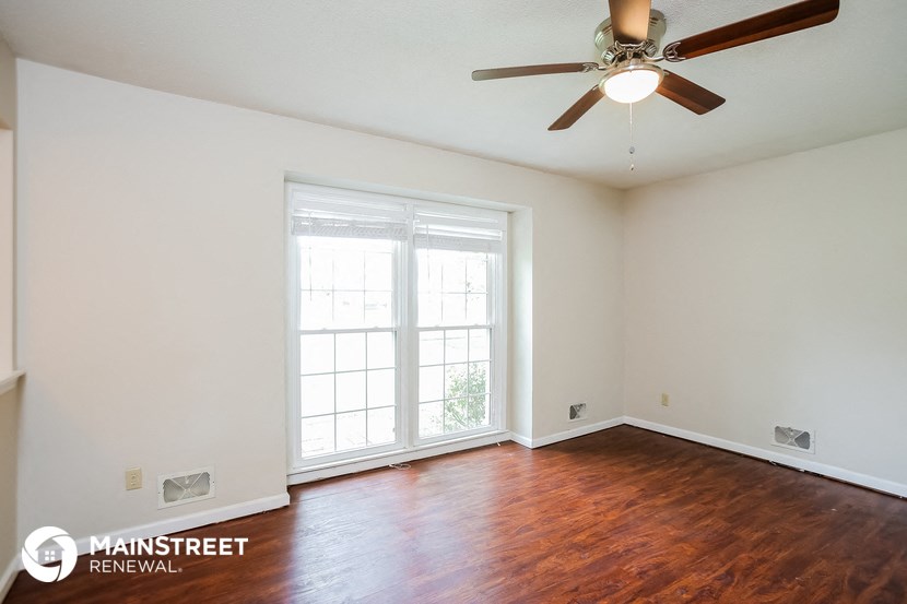 a living room with wood floors and a ceiling fan