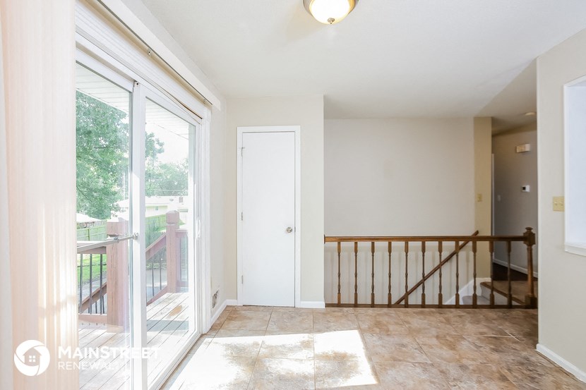 a living room with a staircase and a door to a balcony