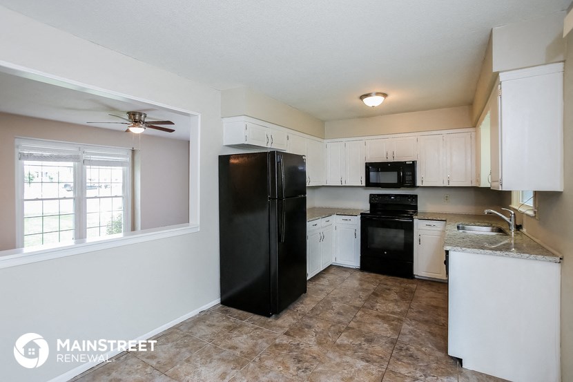 a kitchen with white cabinets and a black refrigerator