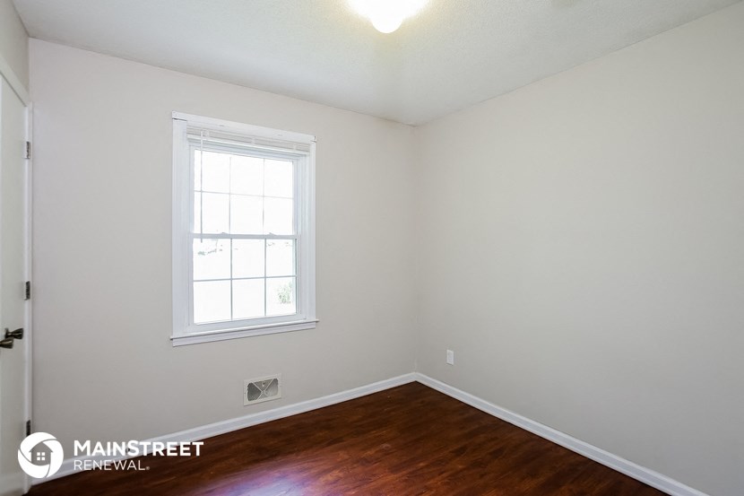 a bedroom with wood flooring and a window