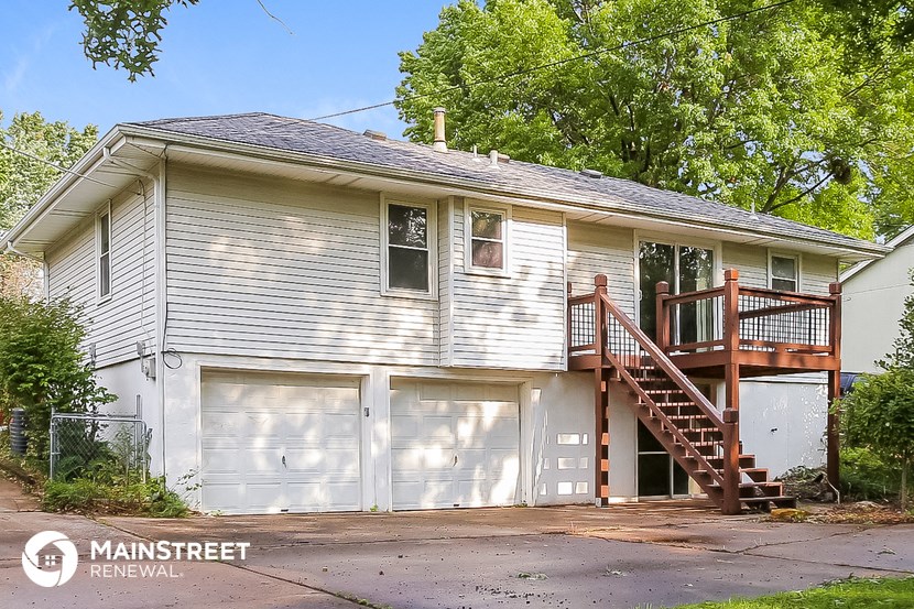 a white house with two garage doors and a deck