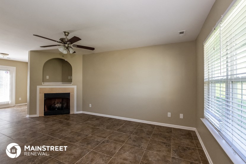 a living room with a fireplace and a ceiling fan