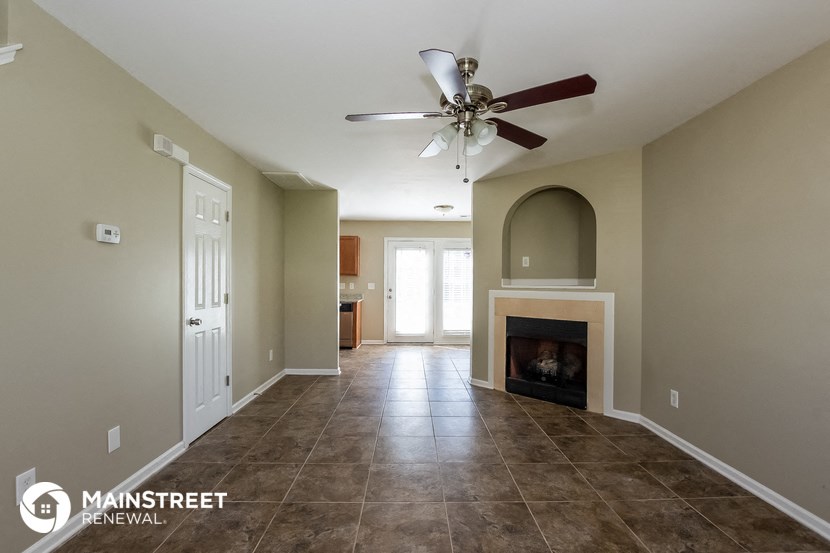 a living room with a fireplace and a ceiling fan