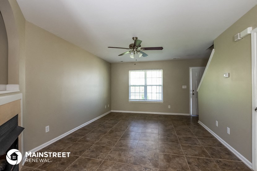 the spacious living room with tile flooring and a ceiling fan