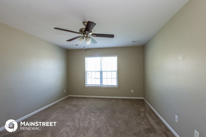 an empty room with a ceiling fan and a window
