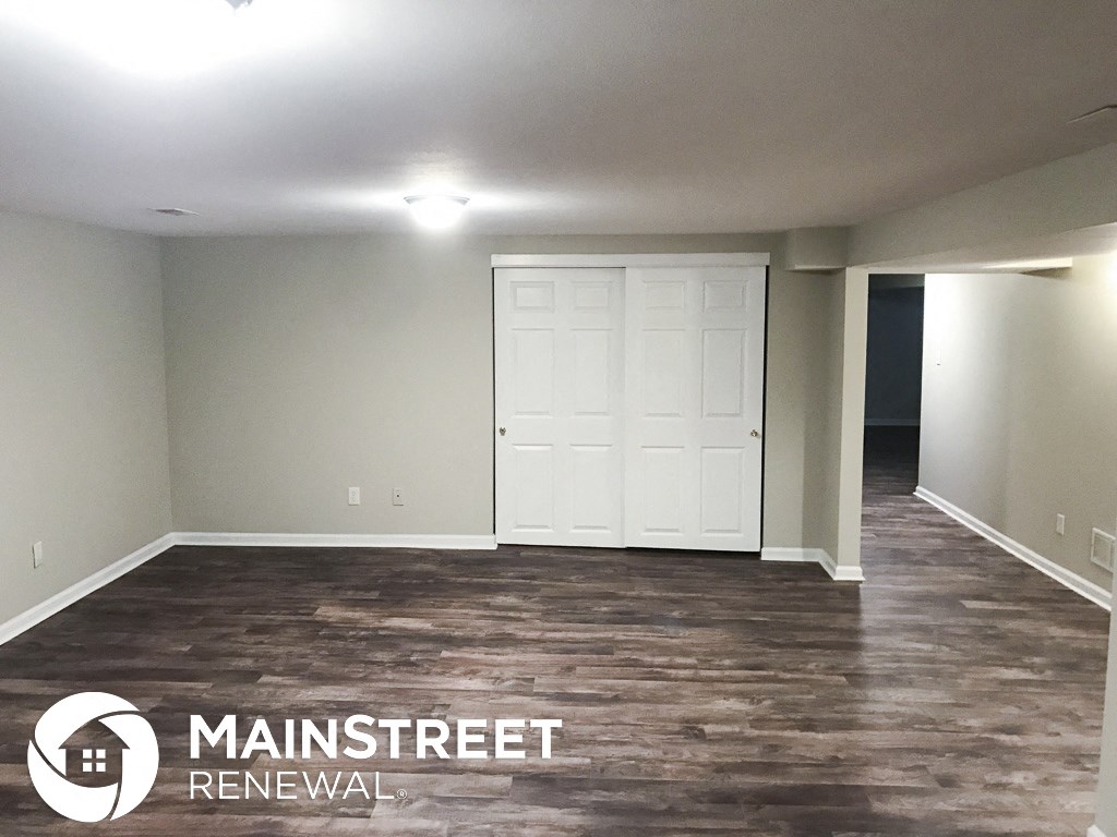 an empty living room with a white door and wood floors