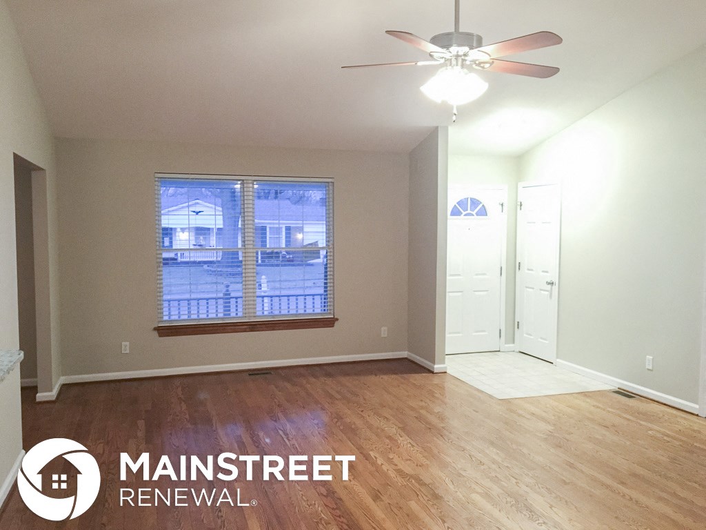 an empty living room with a window and a ceiling fan