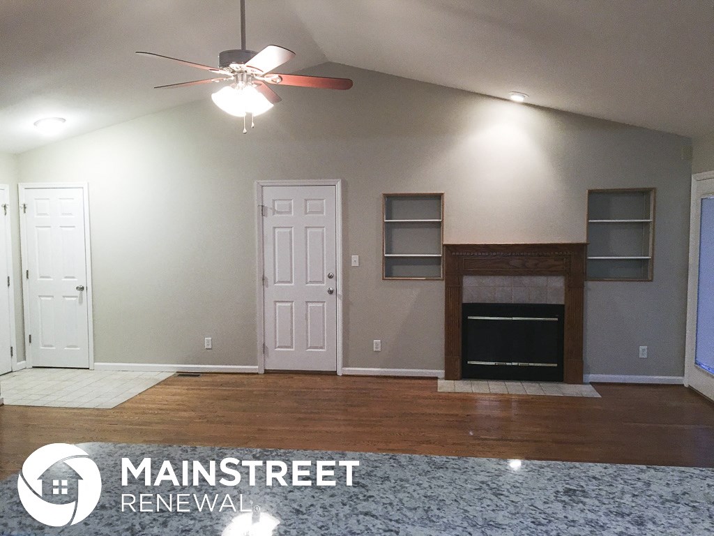 an empty living room with a fireplace and a ceiling fan