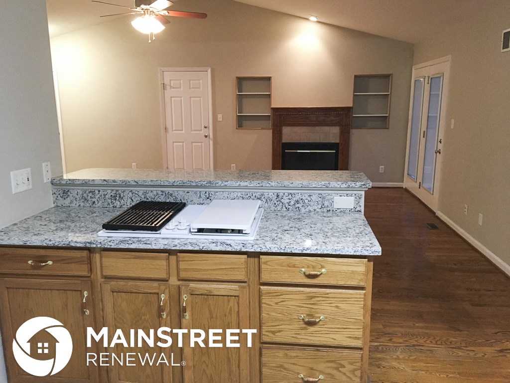 a renovated kitchen with granite counter tops and wooden cabinets