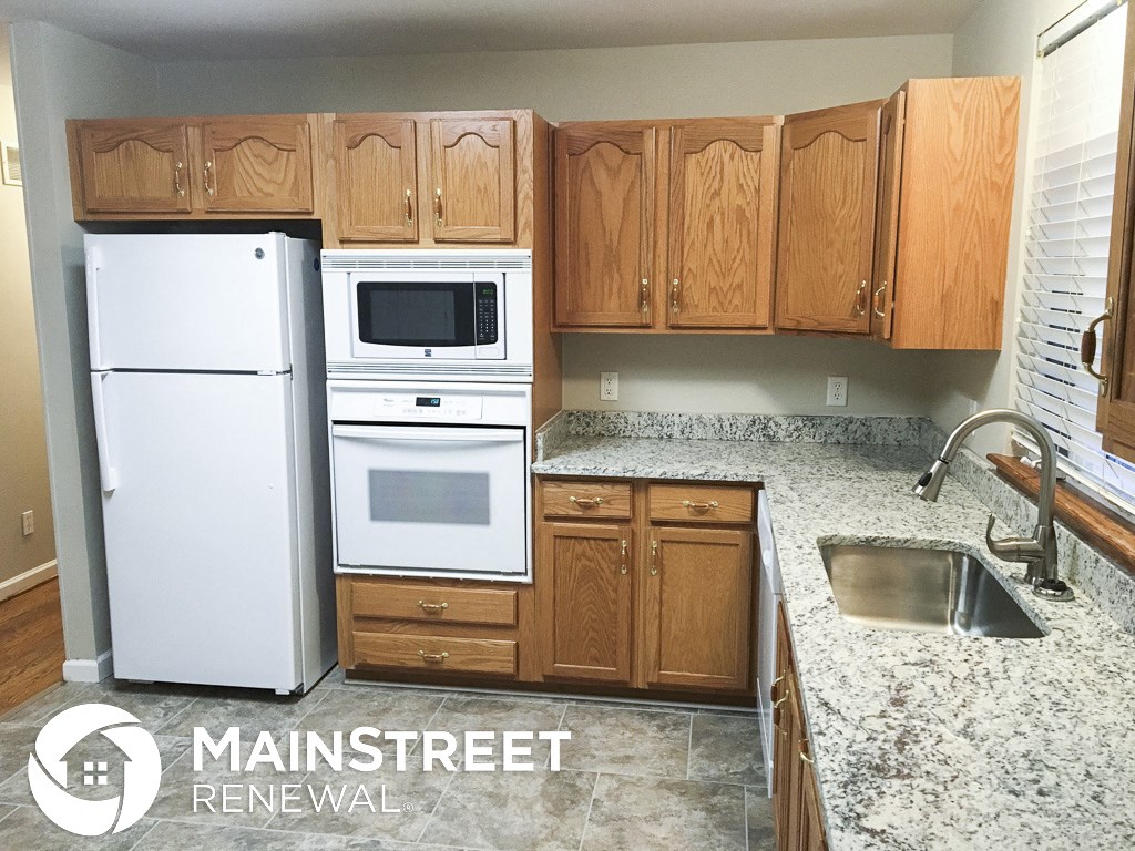 a small kitchen with white appliances and wooden cabinets