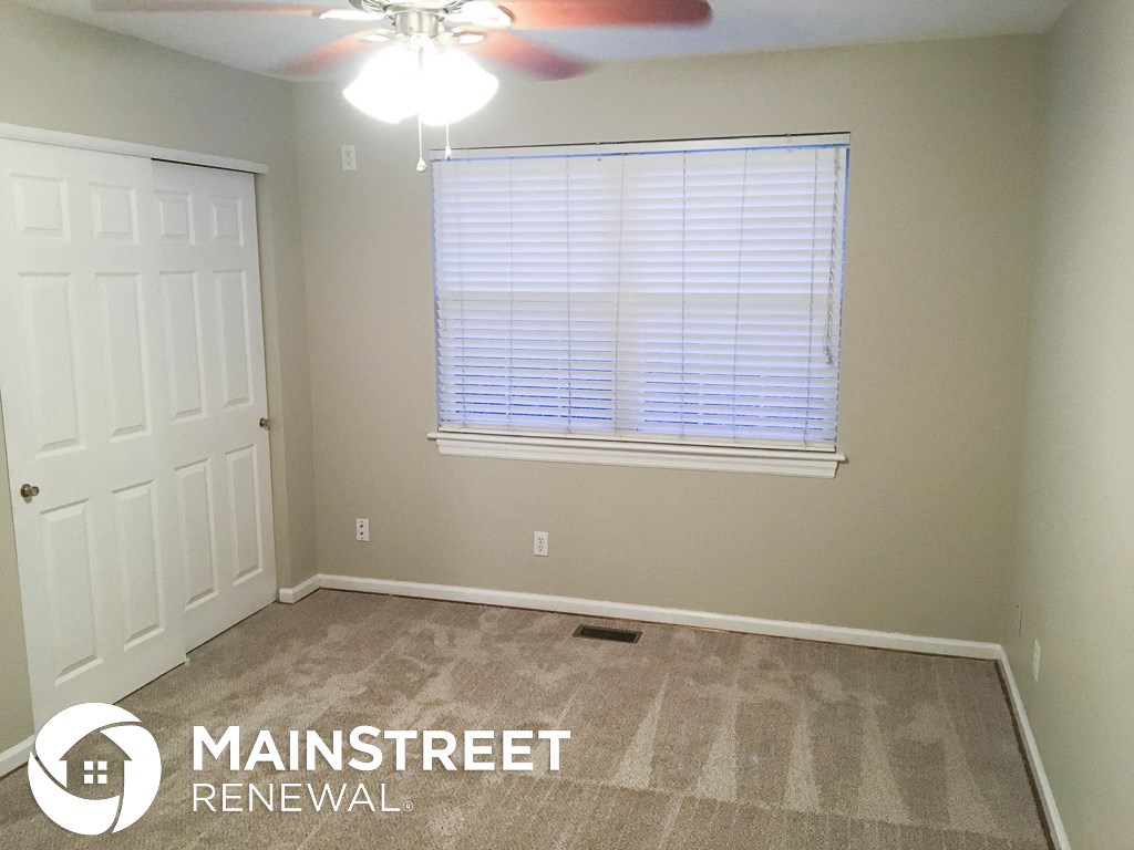 an empty room with a window and a ceiling fan