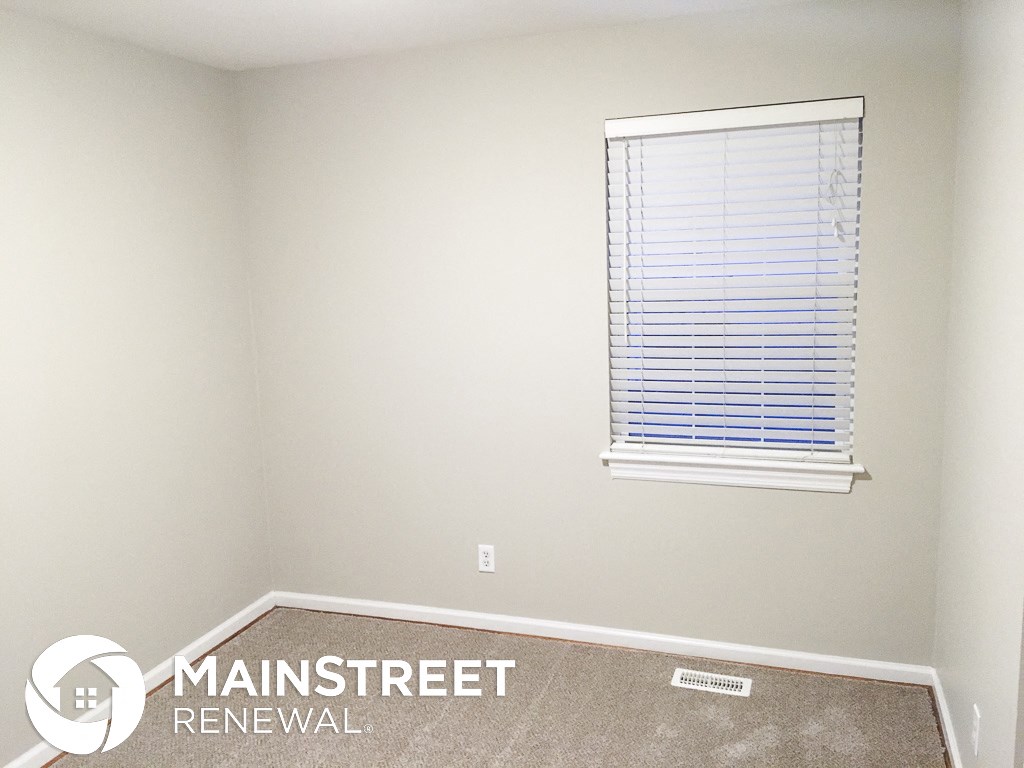 a small room with a window and a carpet