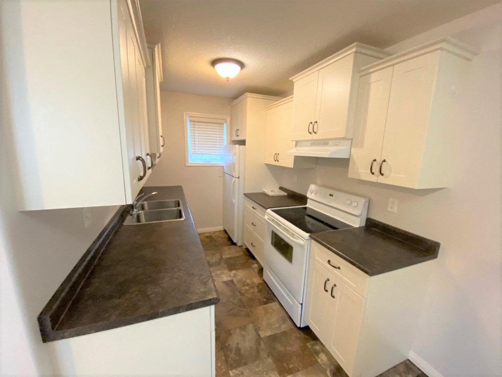 a kitchen with white cabinets and a stove and a sink
