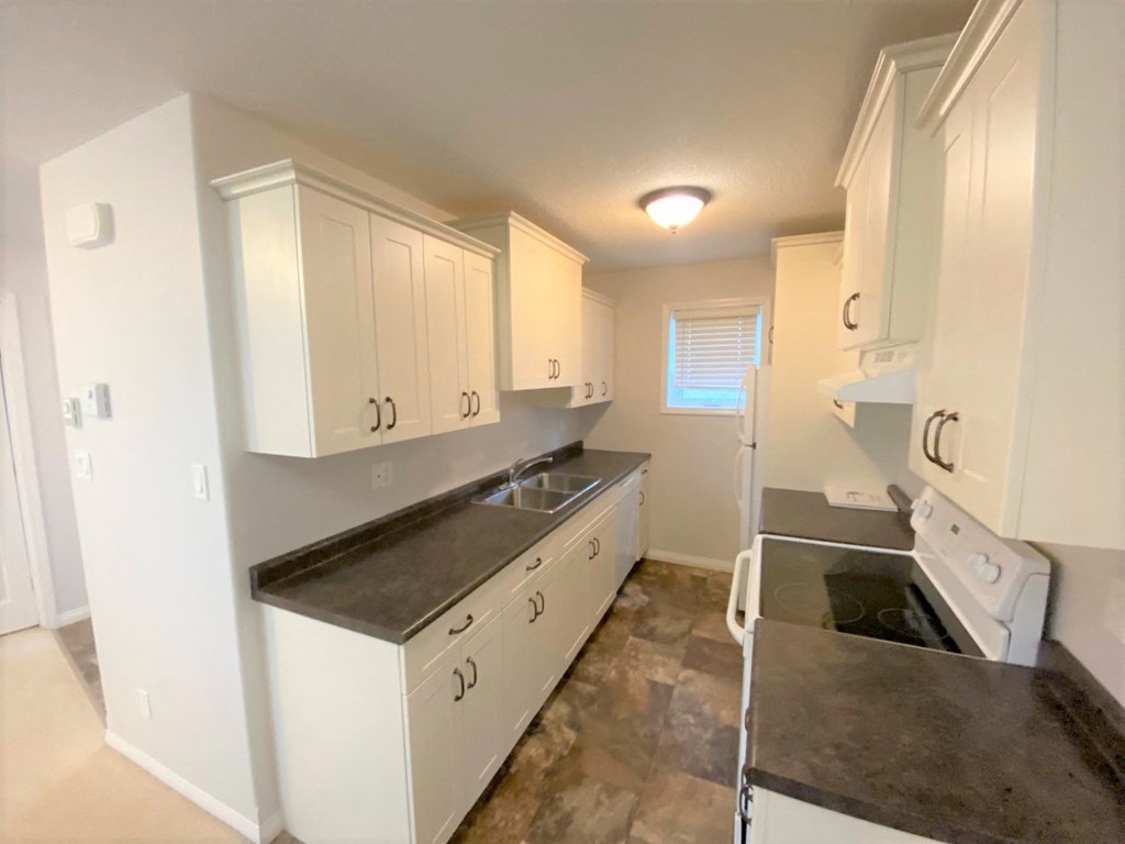 a kitchen with white cabinets and black counter tops and a stove