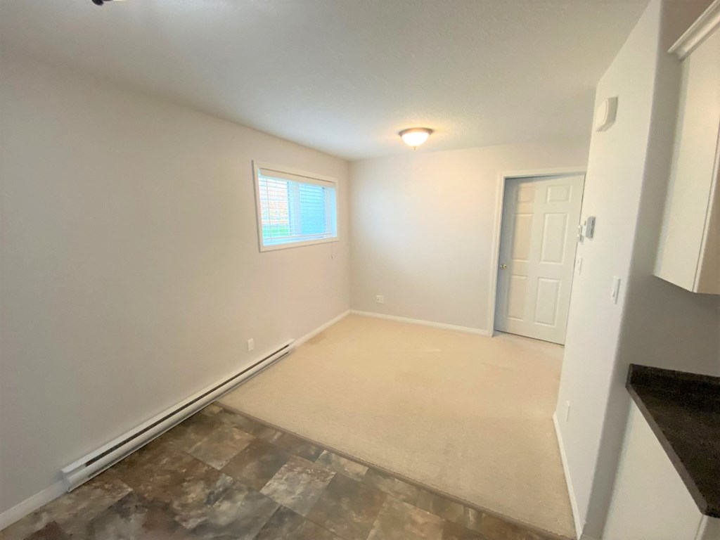 a empty room with a white wall and a door and a window