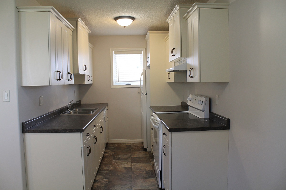 an empty kitchen with white appliances and white cabinets