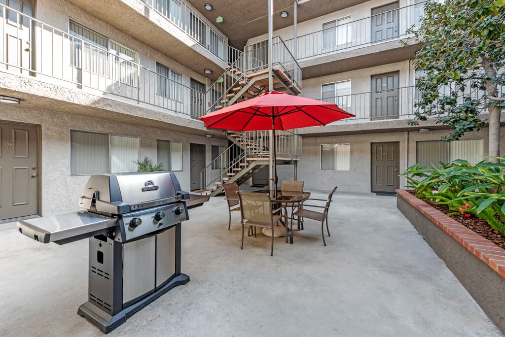 a patio with a grill and a table with an umbrella
