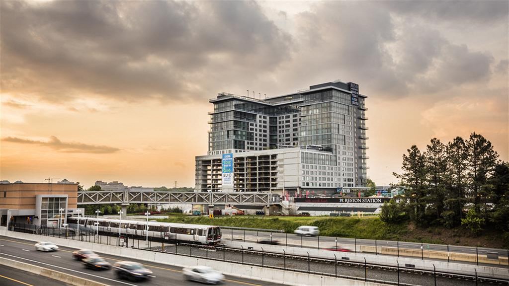 a high rise building next to a freeway and a train
