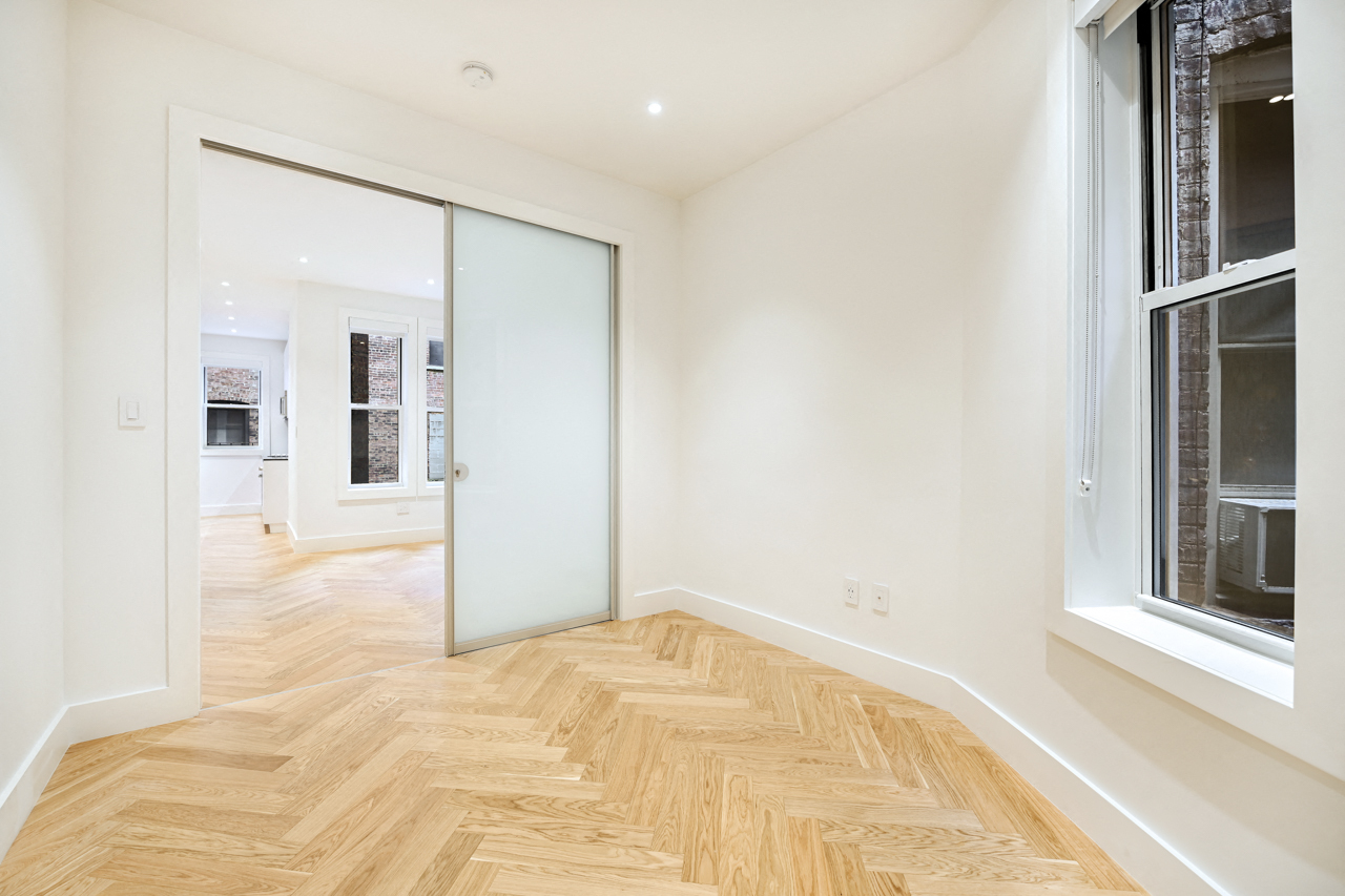 a living room with a glass door and a wooden floor