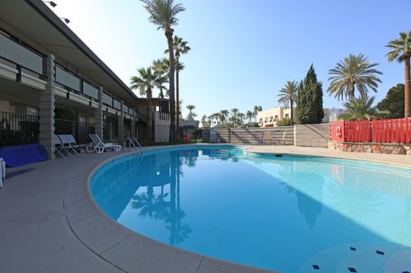 A swimming pool with a blue tinted water and white lounge chairs.