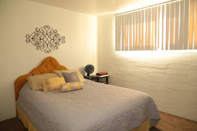 A bedroom with a bed, a wall clock, and a decorative piece on the wall.