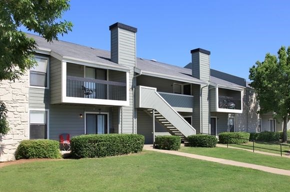 an apartment building with a green lawn and a staircase