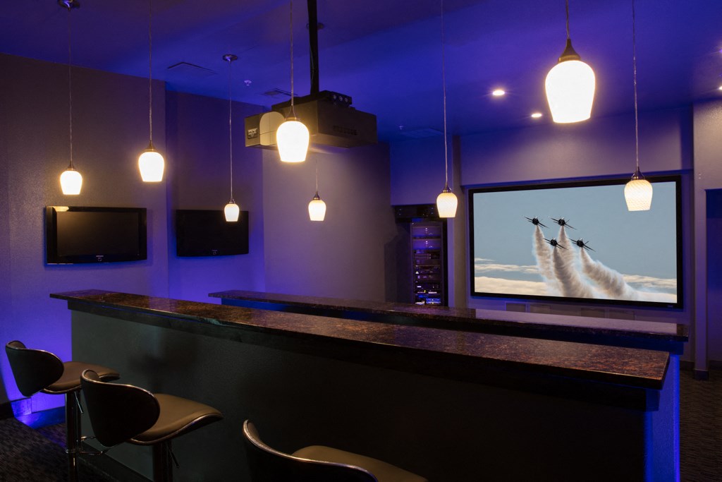 a bar with chairs and a screen in a dark room