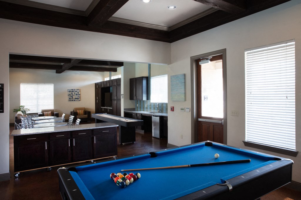 a pool table in a living room with a kitchen