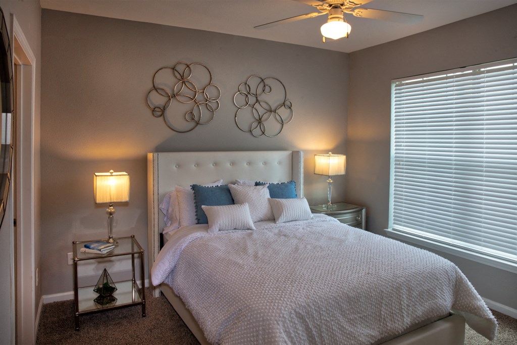 a bedroom with a bed and two lamps and a ceiling fan