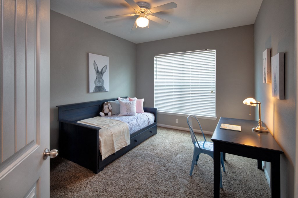 a bedroom with a bed and a desk and a ceiling fan