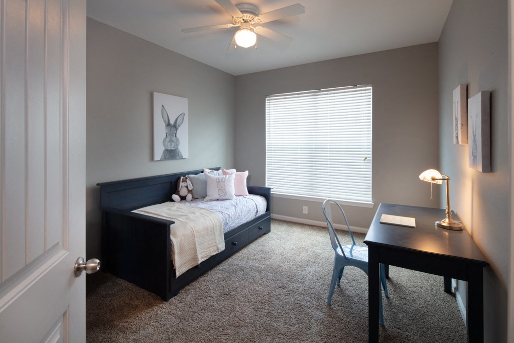 a bedroom with a bed and a desk and a ceiling fan