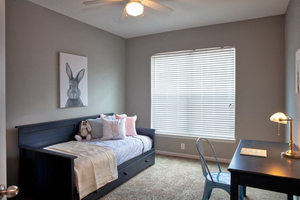 a bedroom with a bed and a desk and a window