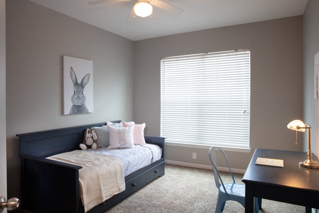 a bedroom with a bed and a desk and a window