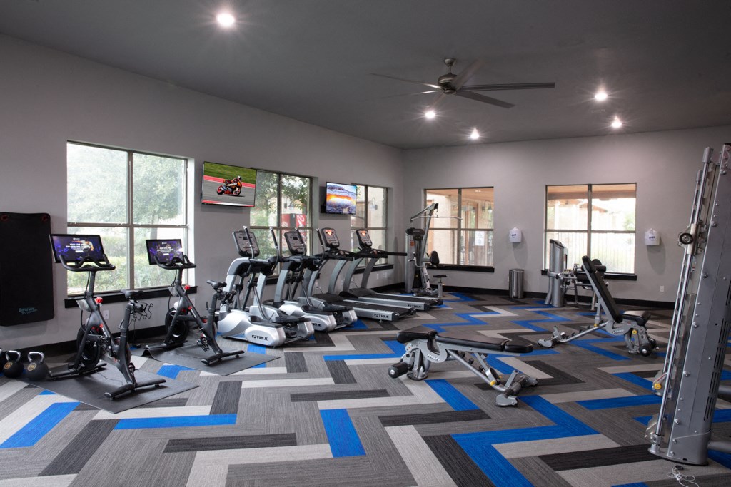 a gym with treadmills and other exercise equipment in a building with windows