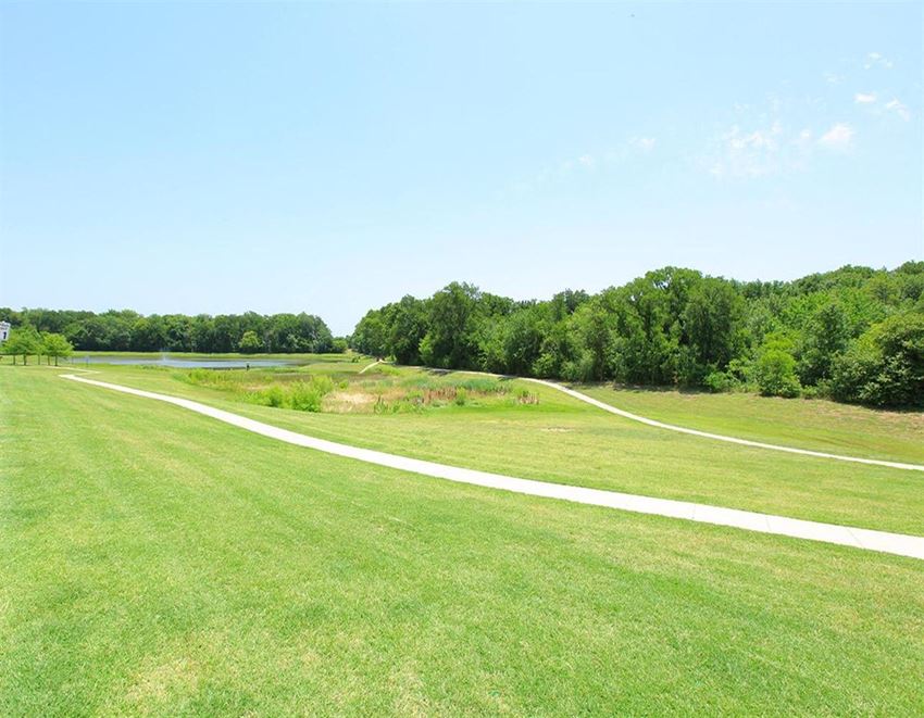 a grassy field with a path leading to a body of water