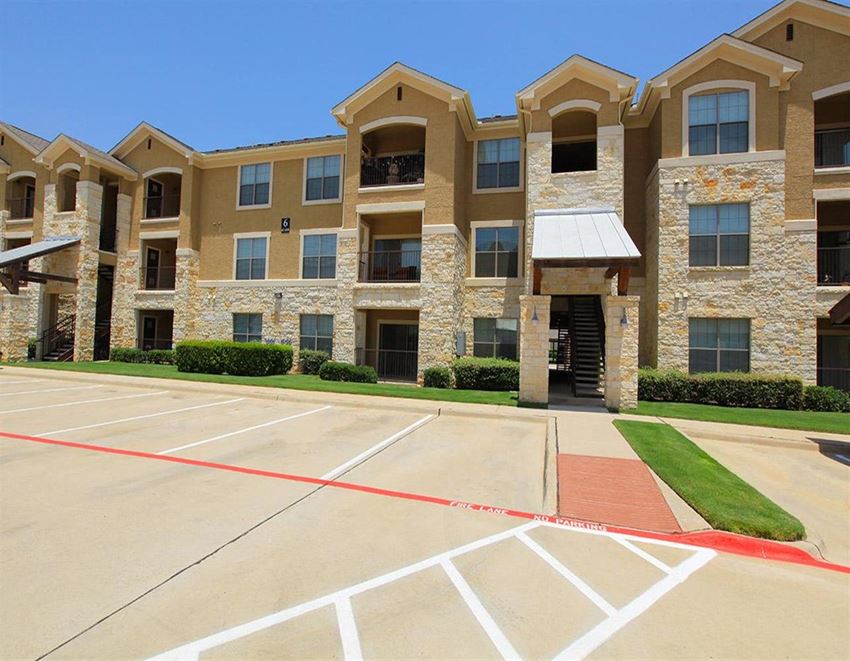an empty parking lot in front of an apartment building