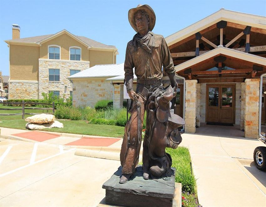 a statue of a cowboy sitting on a horse in front of a building