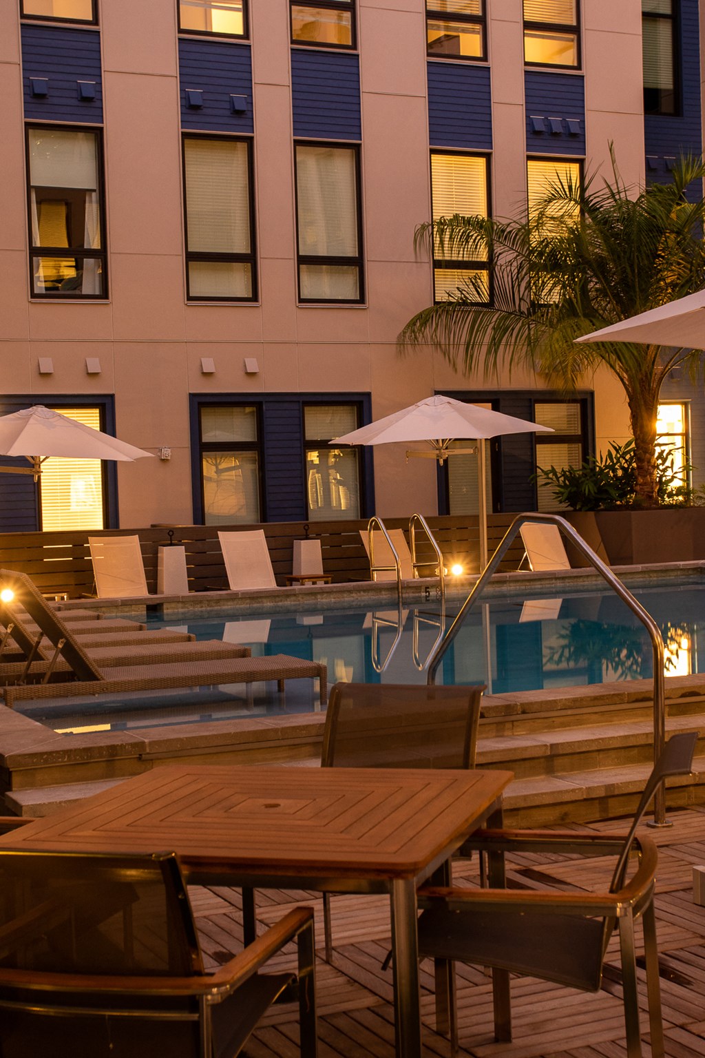 a hotel pool with tables and umbrellas at night