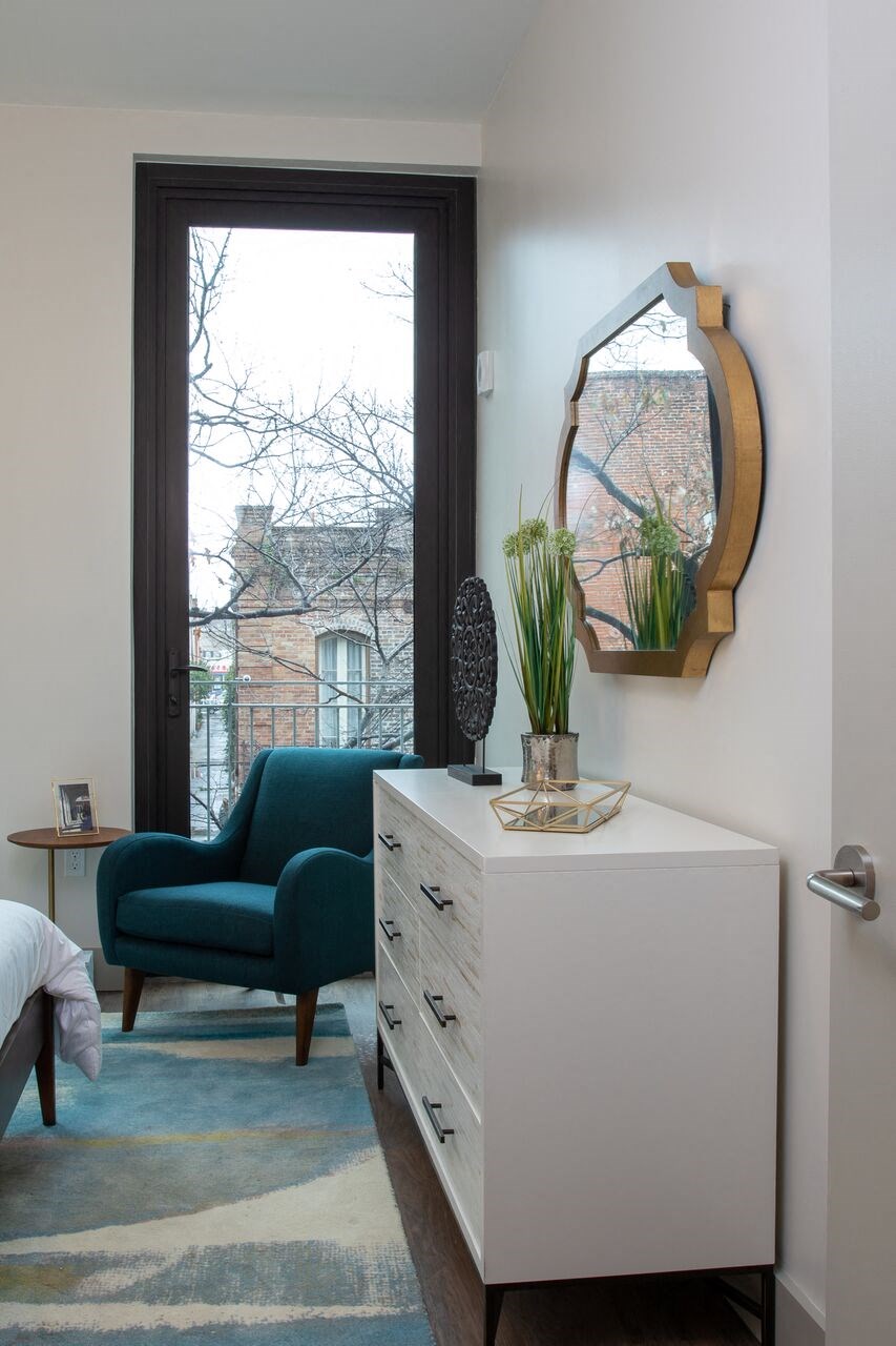 a living room with a window and a dresser with a mirror