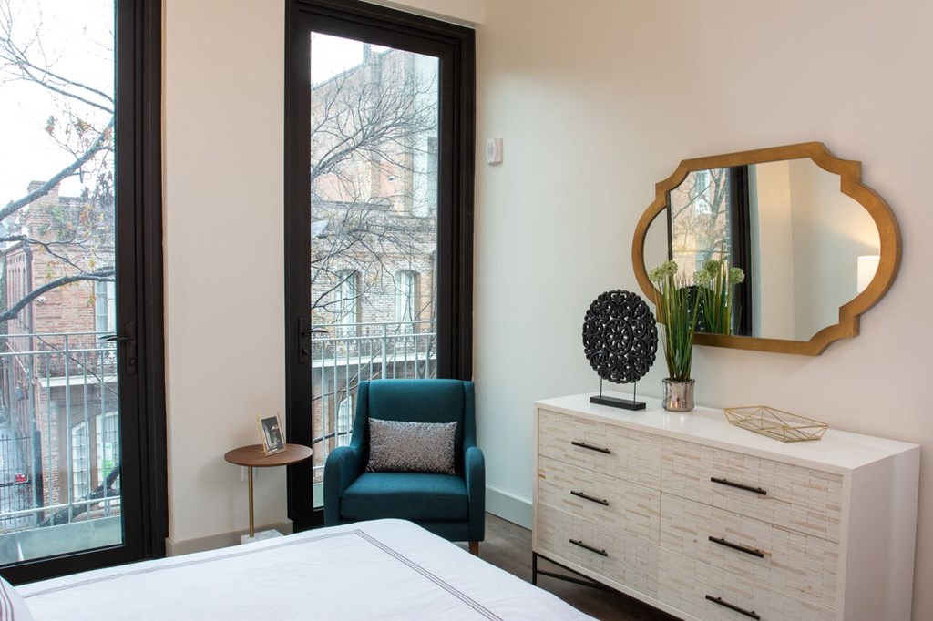 a bedroom with a large window and a dresser with a mirror